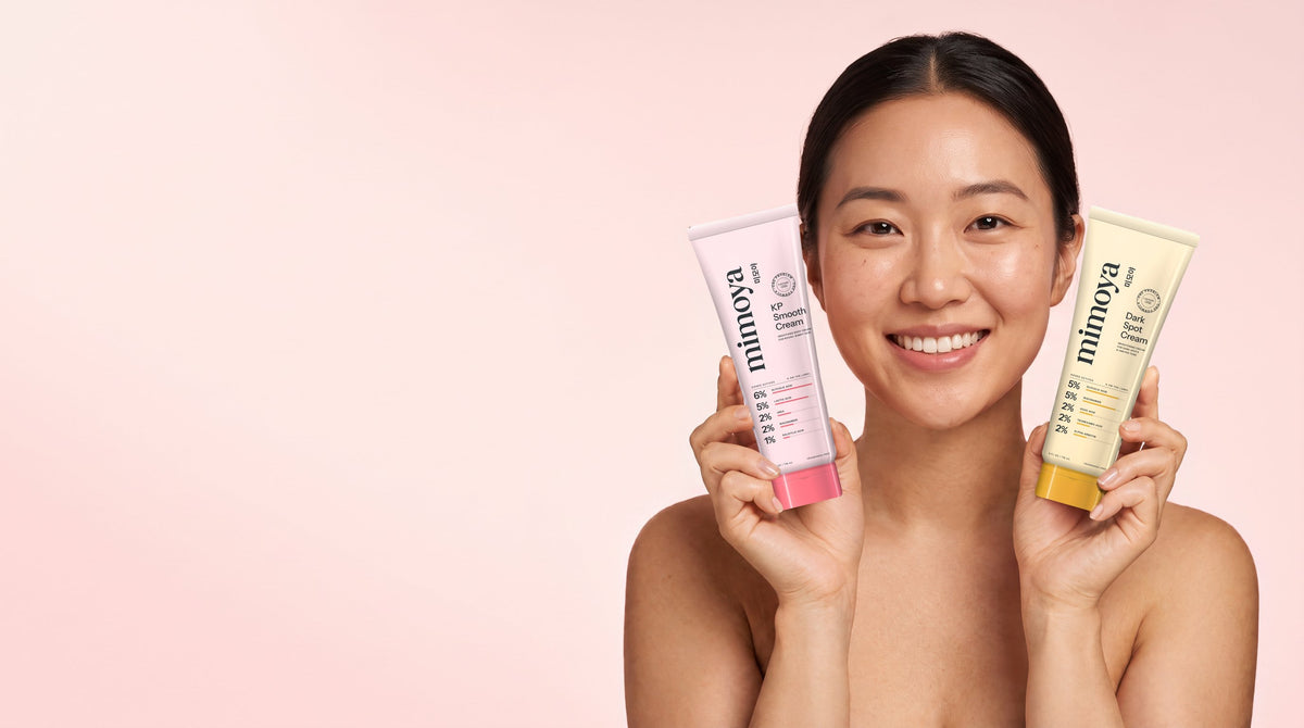 Smiling woman holding MIMOYA KP Smooth Cream for keratosis pilaris and MIMOYA Dark Spot Cream for hyperpigmentation